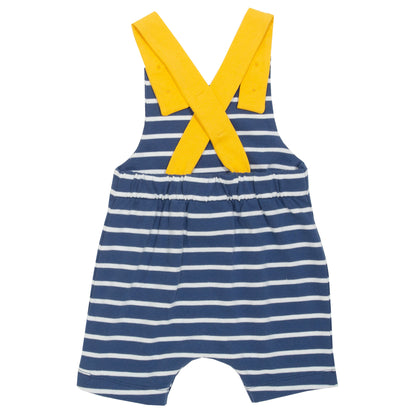 Vista trasera de la Jardinera Marinera de algodón orgánico con diseño a rayas azul marino y crema, mostrando los tirantes ajustables cruzados en color amarillo y el ajuste cómodo para bebés en movimiento.