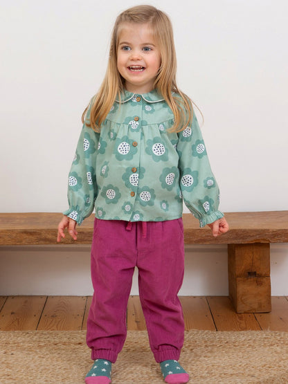 Niña vistiendo pantalones de cotelé rosa berry, combinando estilo y comodidad con un diseño holgado y una textura suave para el día a día.