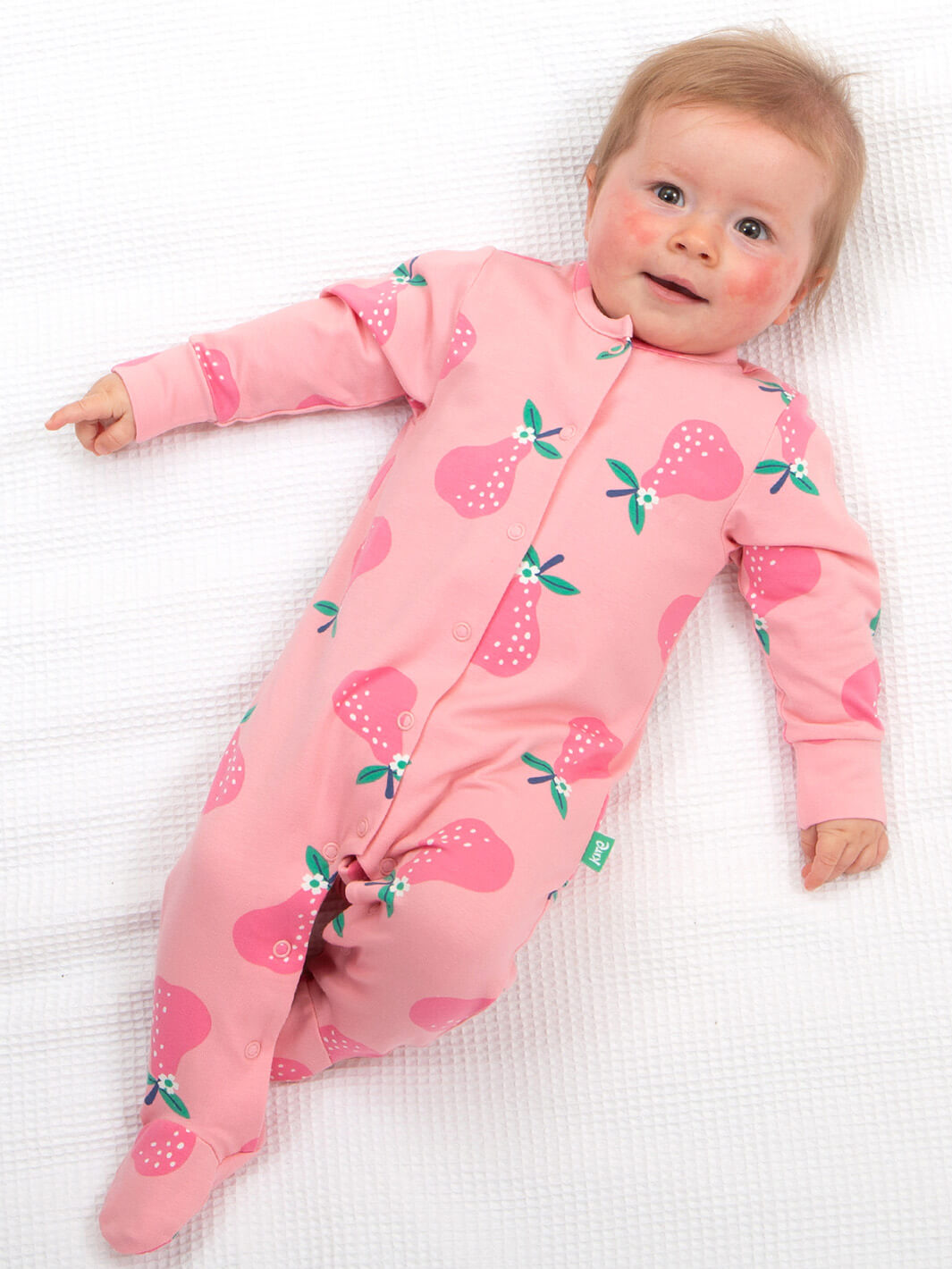 Bebé usando pijama rosa de algodón orgánico con estampado de peras