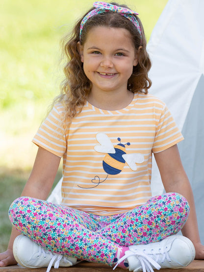 Niña vistiendo la Polera Abeja Reina de algodón orgánico con calzas, combinación perfecta para el verano.
