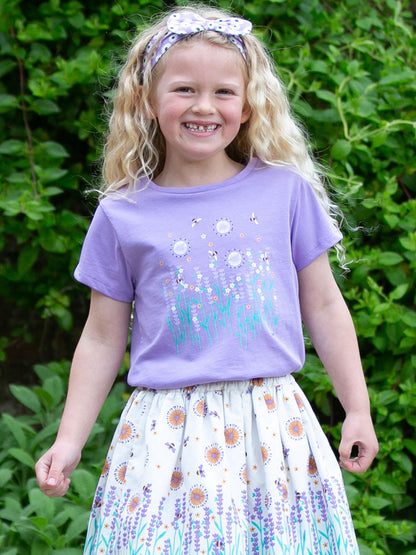 Niña usando la Polera Amor Lavanda de algodón orgánico, combinada con una falda para un look fresco y femenino.