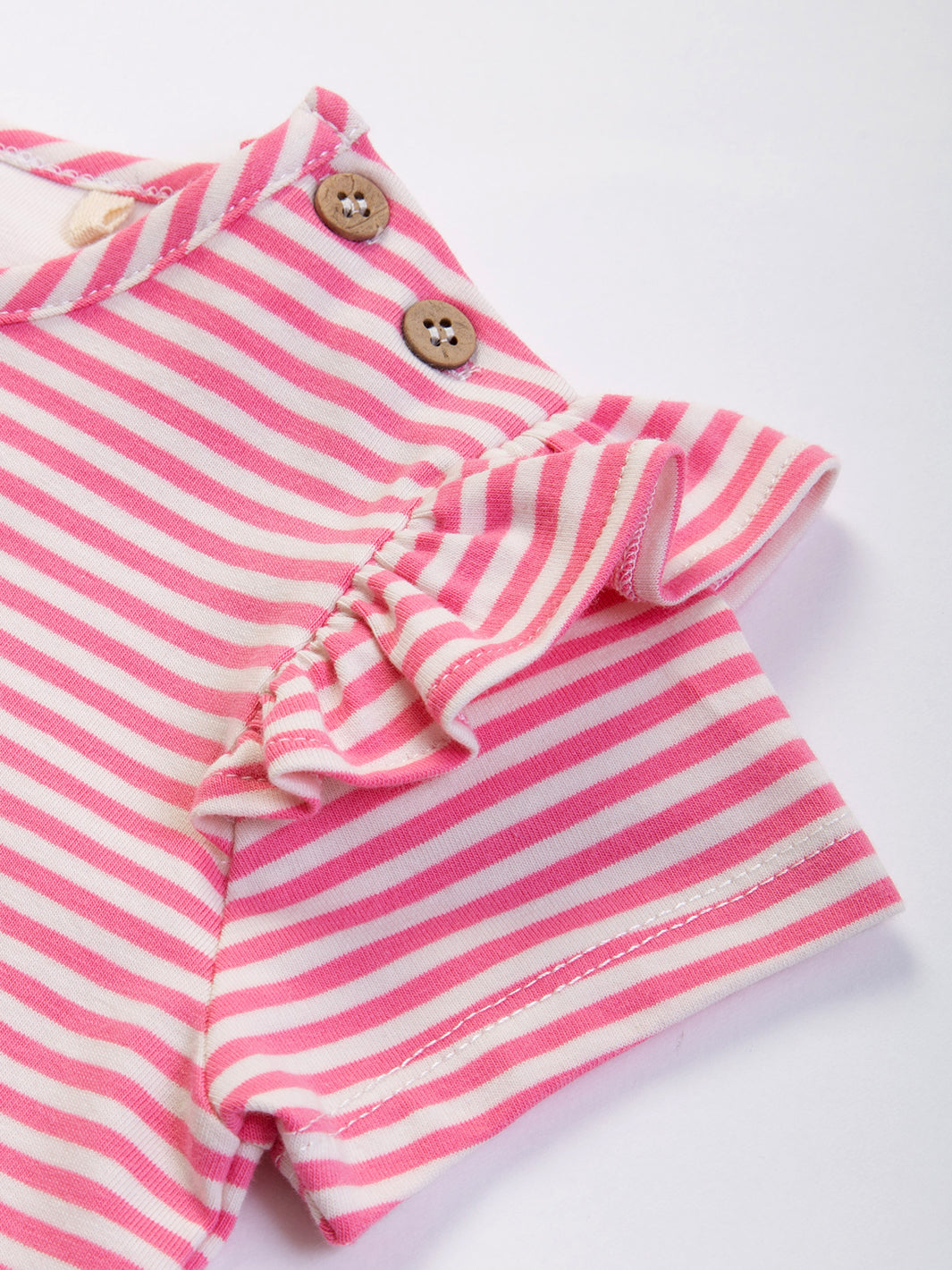 Botones de coco y detalle de volantes en las mangas en la Polera con Alitas de algodón orgánico, diseño delicado y ecológico.