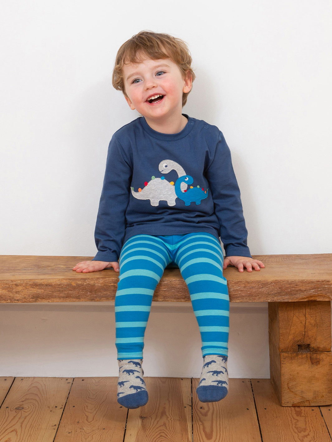 Niño vistiendo la Polera Dino Amigos de algodón orgánico, combinada con calzas para un look divertido y cómodo.