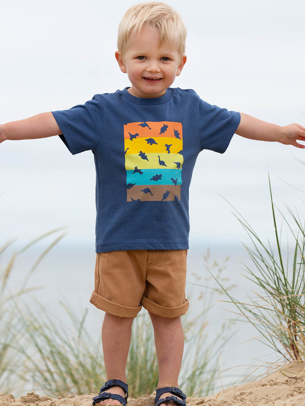 Niño usando la Polera Dino Dot de algodón orgánico, combinada con shorts para un look fresco y aventurero.