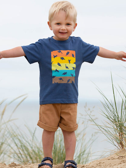 Niño usando la Polera Dino Dot de algodón orgánico, combinada con shorts para un look fresco y aventurero.