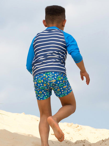 Niño disfrutando en la playa vistiendo la Polera UV Marinero, ideal para días de sol y agua.