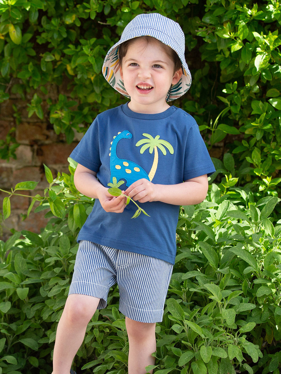 Niño usando la Polera Tierra de Dinosaurios de algodón orgánico, combinada con pantalón para un look aventurero y cómodo.