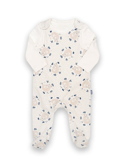 Conjunto de algodón orgánico para bebé, compuesto por una jardinera con estampado de osito abrazable y un body color crema con cuello envolvente y bordado de oso en el brazo.
